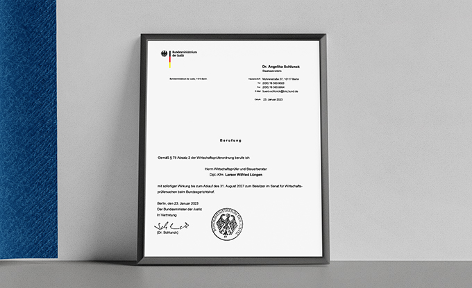 Ein gerahmtes Dokument auf einem Tisch, das eine offizielle Mitteilung mit dem Bundesadler und dem Logo der Bundesregierung enthält. Das Dokument ist an Dr. Angelika Schmid adressiert und enthält Informationen zu einer Veranstaltung sowie ein Datum.