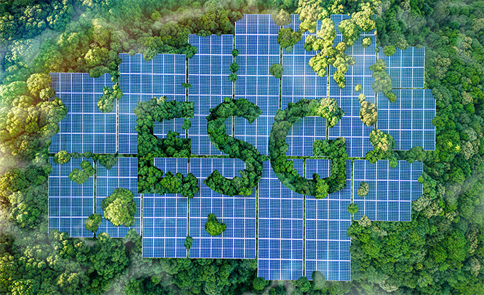 Eine große Ansammlung von Solarpanelen im Wald bildet die Buchstaben „ESG“ (Umwelt, Soziale Verantwortung und Unternehmensführung) aus, umgeben von üppigem grünem Wald.