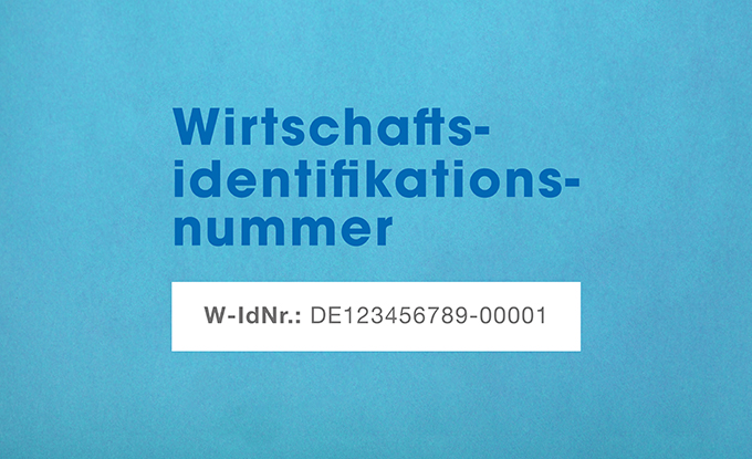 Ein hellblauer Hintergrund zeigt den Text "Wirtschafts-identifikationsnummer" in großen, fetten Buchstaben sowie eine untere Zeile mit der Aufschrift "W-IdNr.: DE123456789-00001" in kleinerer Schrift.